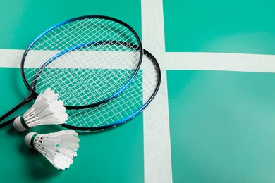 Photo of Feather badminton shuttlecocks and rackets on green table. Space for text