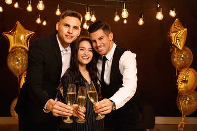 Photo of Happy friends with glasses of sparkling wine celebrating New Year indoors