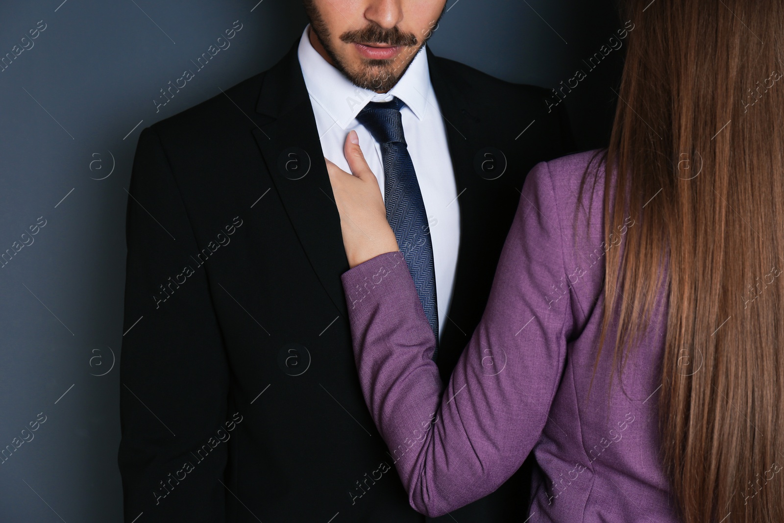 Photo of Woman molesting her male colleague on dark background, closeup. Sexual harassment at work