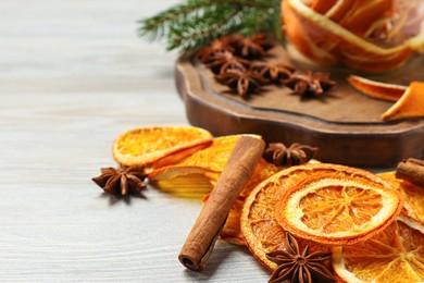 Photo of Dry orange slices, anise stars and cinnamon sticks on white wooden table, closeup. Space for text