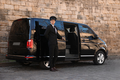 Photo of Driver opening door of luxury car on street. Chauffeur service