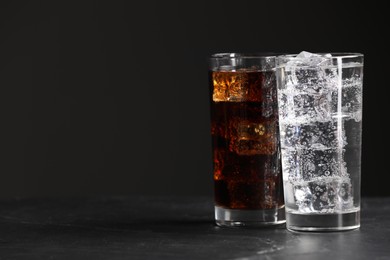 Photo of Glasses of different refreshing soda water with ice cubes on grey table, space for text