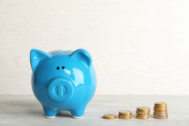 Piggy bank with coins on light table. Space for text