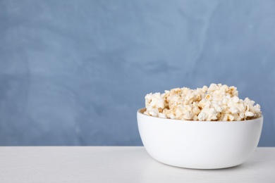 Photo of Delicious popcorn on white wooden table. Space for text