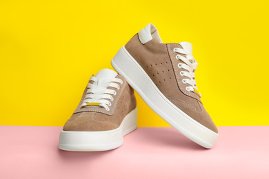 Stylish brown shoes on pink paper against yellow background