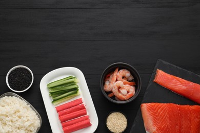 Photo of Making sushi rolls. Flat lay composition with ingredients on black wooden table. Space for text
