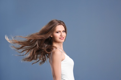 Portrait of young woman with long beautiful hair on grey background