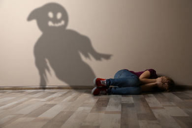 Image of Scared little girl suffering from sciophobia and phantom behind her. Irrational fear of shadows