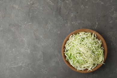 Photo of Chopped cabbage in bowl on grey table, top view. Space for text