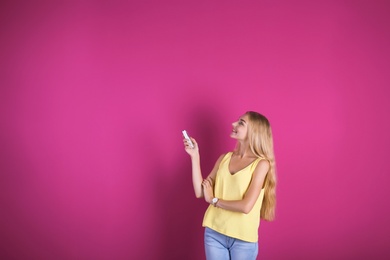 Photo of Young woman operating air conditioner with remote control on color background