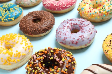 Photo of Delicious glazed donuts on light blue background, closeup