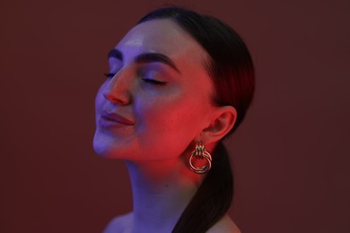 Photo of Portrait of beautiful young woman on color background in neon lights, closeup