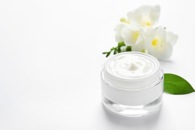 Photo of Jar of cream and flowers on white background. Professional cosmetic products