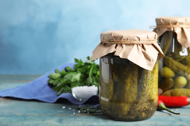 Photo of Jars with pickled cucumbers on blue wooden table, space for text