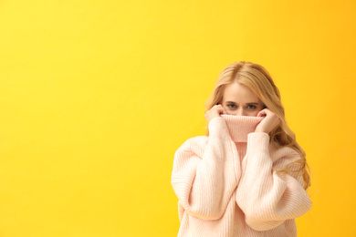 Photo of Beautiful young woman wearing warm pink sweater on yellow background. Space for text