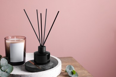 Photo of Composition with aromatic reed air freshener on wooden table near pink wall, space for text