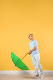 Photo of Man with green umbrella near color wall