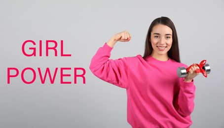 Image of 8 March greeting card. Phrase Girl Power and young woman holding dumbbell on light background