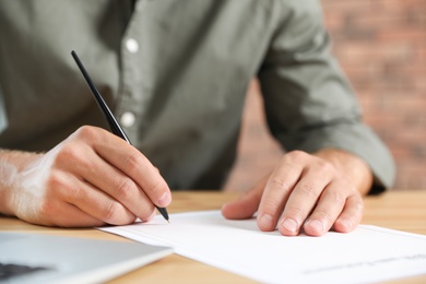Photo of Male notary signing document at table in office, closeup