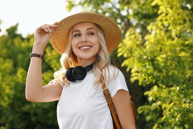 Photo of Happy young woman with headphones in park on spring day