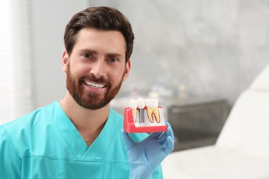 Photo of Dentist holding educational model of dental implant in clinic. Space for text