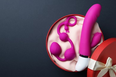 Photo of Pink sex toys in gift box on dark blue background, top view. Space for text