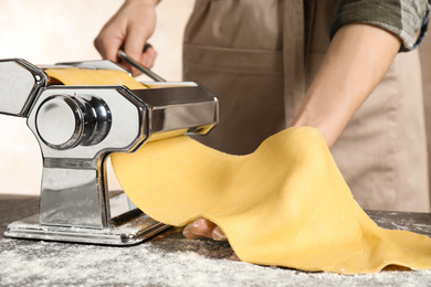 Photo of Woman preparing dough with pasta maker machine at table, closeup