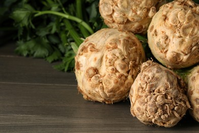 Photo of Fresh raw celery roots on wooden table, closeup. Space for text