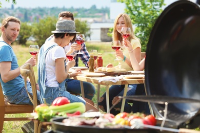 Photo of Young people having barbecue with modern grill outdoors