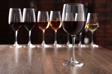 Photo of Different tasty wines in glasses on wooden table
