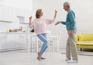 Photo of Happy senior couple dancing together in kitchen