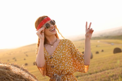 Photo of Beautiful happy hippie woman showing peace sign in field