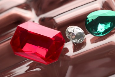 Photo of Different beautiful gemstones for jewelry on color mirror surface, closeup