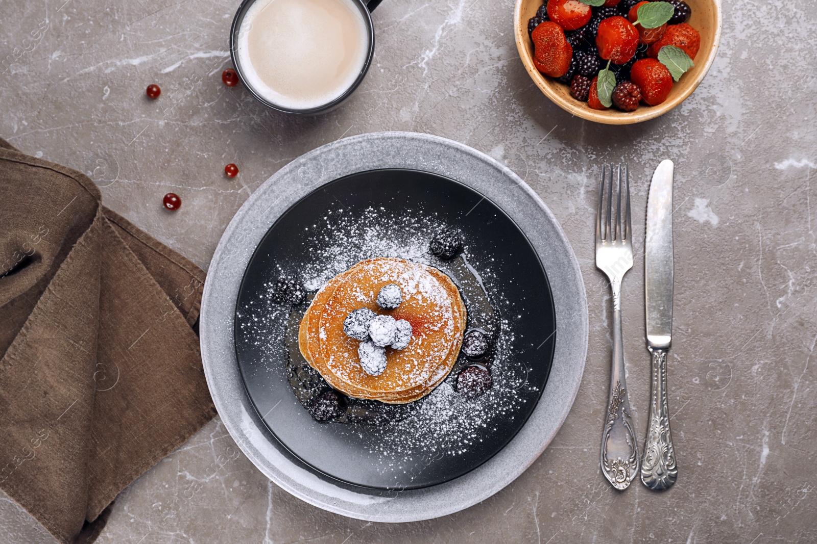 Photo of Delicious pancakes with berries and powdered sugar served for breakfast on table