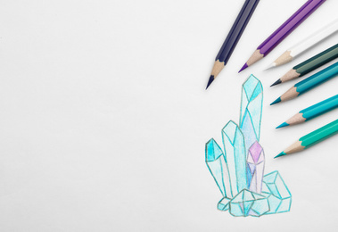 Photo of Drawing of crystals and colorful pencils on white background, top view