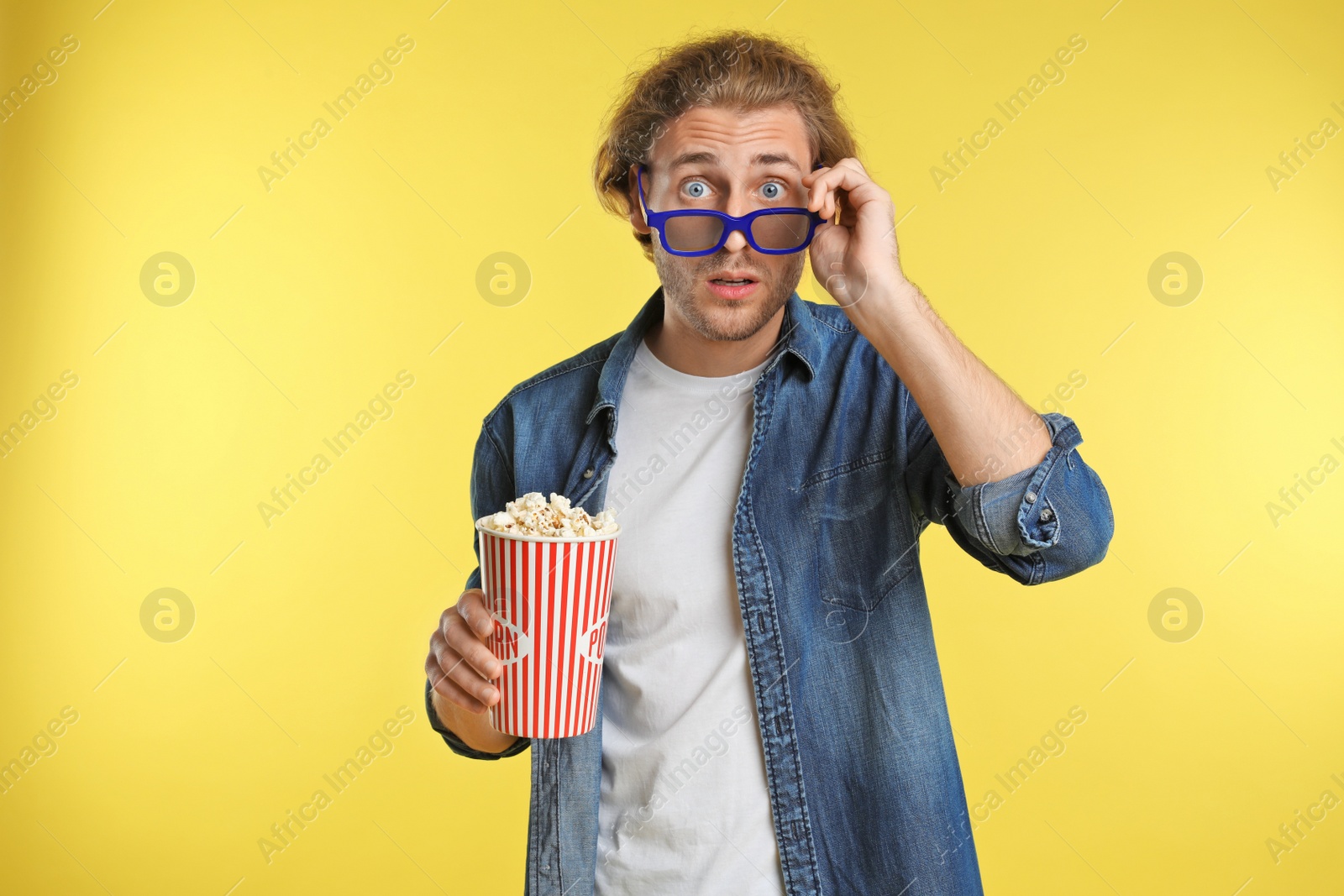 Photo of Emotional man with 3D glasses and popcorn during cinema show on color background