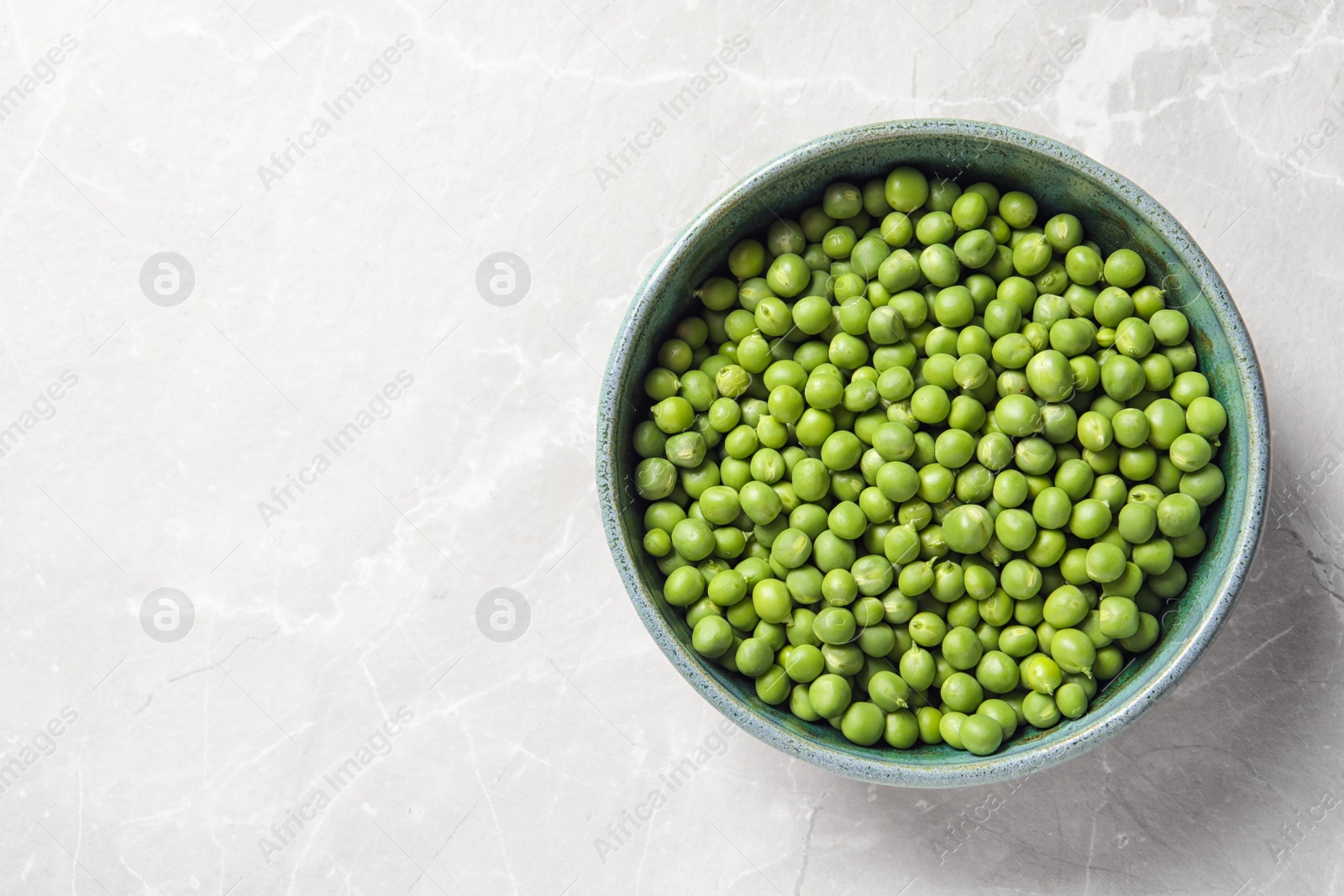 Photo of Bowl with green peas on light background, top view