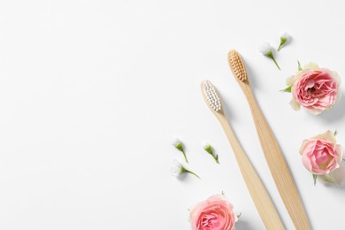 Flat lay composition with toothbrushes and flowers on white background. Space for text