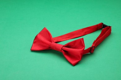 Stylish red bow tie on green background