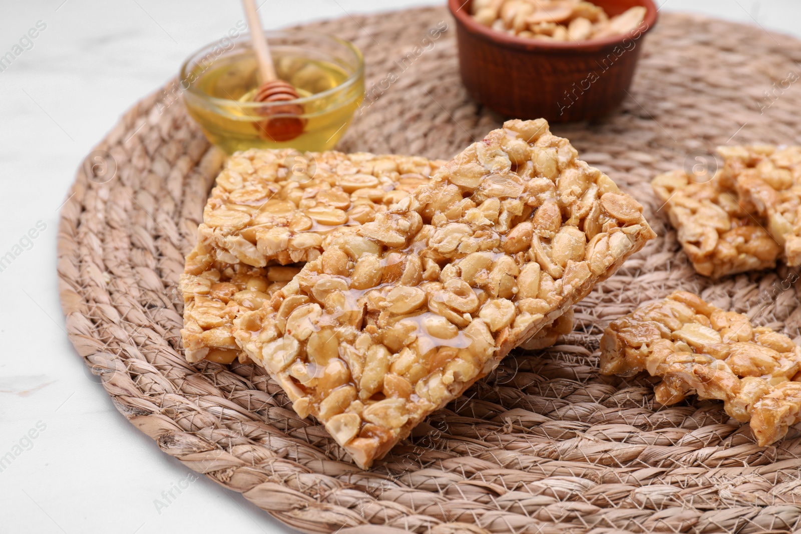 Photo of Delicious peanut bars (kozinaki) and ingredients on white marble table