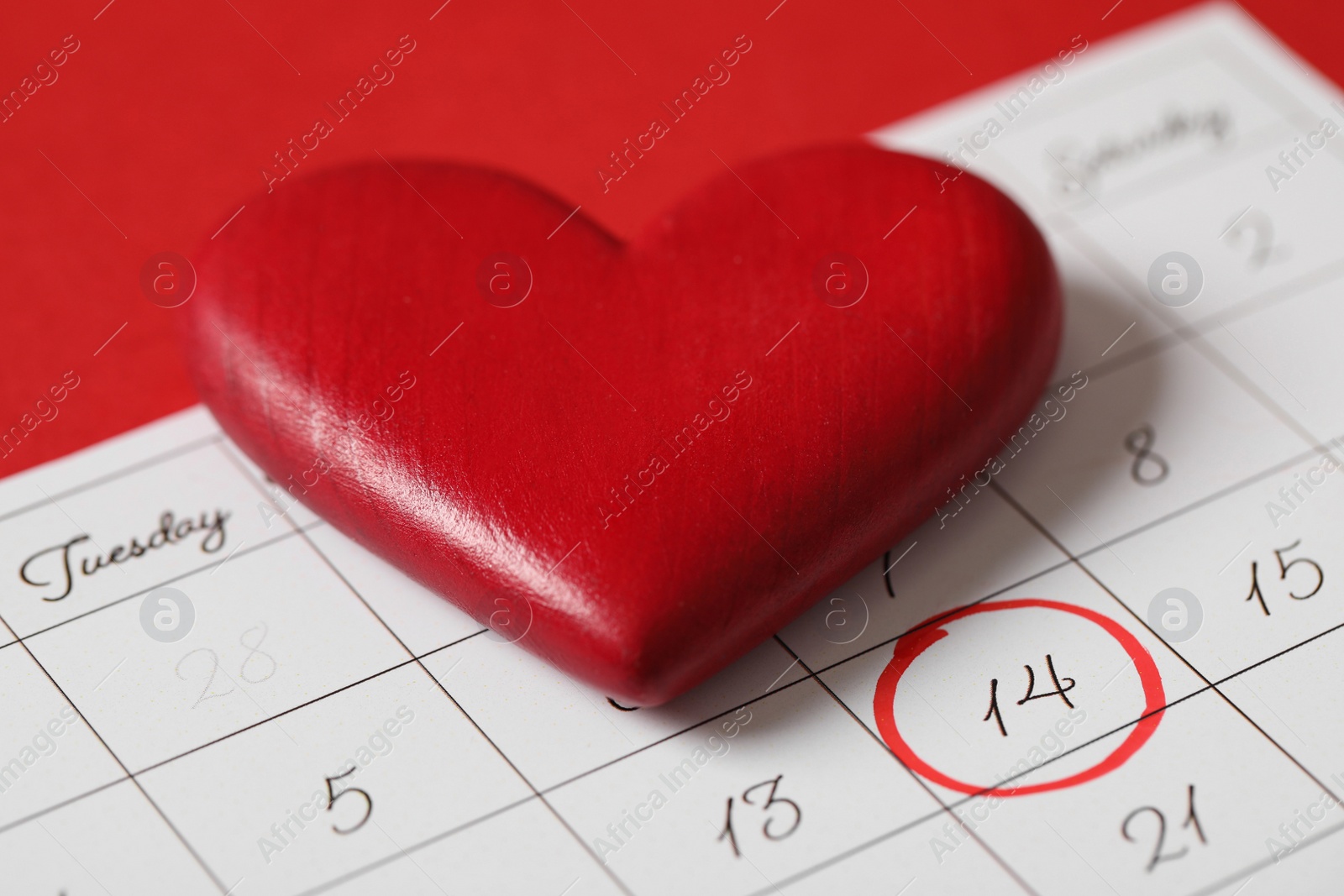 Photo of Calendar with marked Valentine's Day and heart on red background, closeup