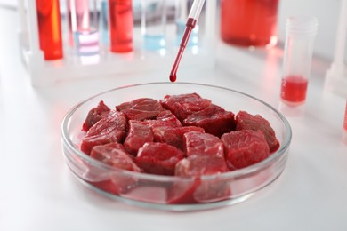 Dripping sample onto raw cultured meat on white table in laboratory, closeup