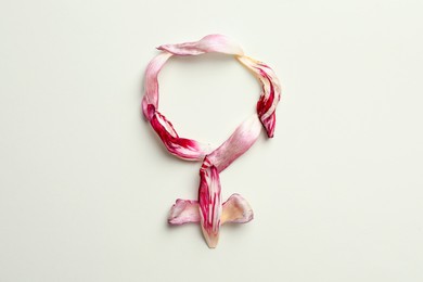 Female gender sign made of tulip petals on beige background, top view. Menopause concept