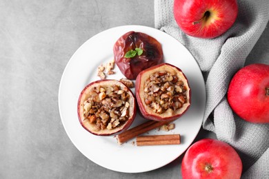 Photo of Tasty baked apples with nuts, honey, cinnamon sticks and mint on gray table, flat lay. Space for text