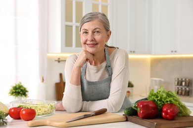 Photo of Happy housewife at white table in kitchen. Cooking process