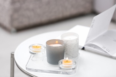 Photo of Burning candles in beautiful holders on white table indoors