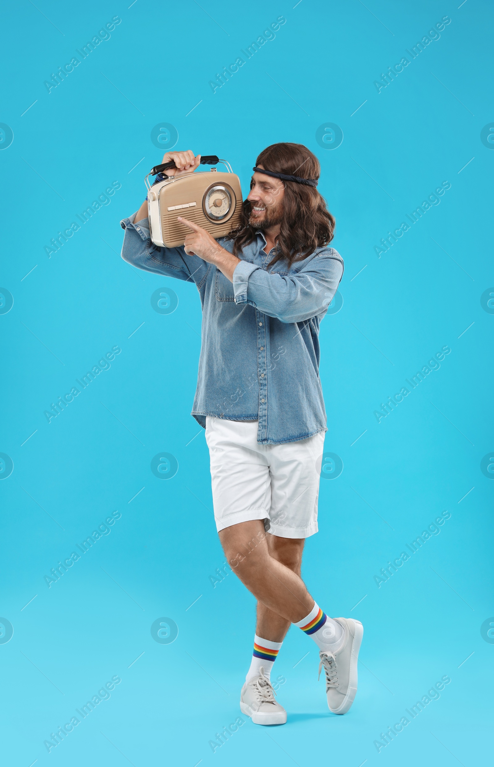 Photo of Stylish hippie man with retro radio receiver on light blue background