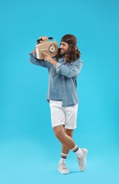 Photo of Stylish hippie man with retro radio receiver on light blue background