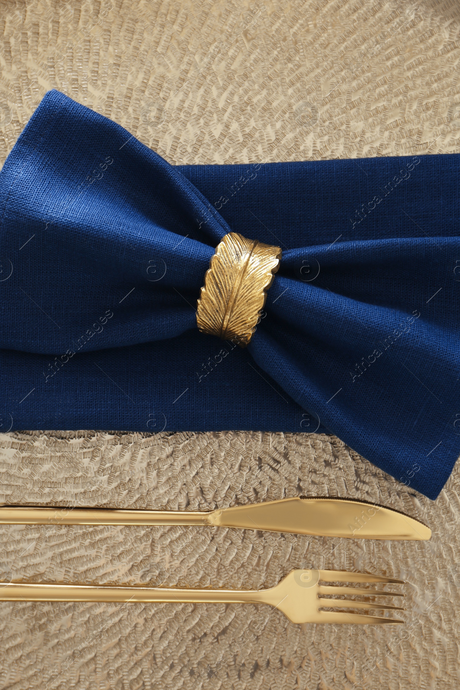 Photo of Blue napkins, decorative ring and cutlery on textured background, top view