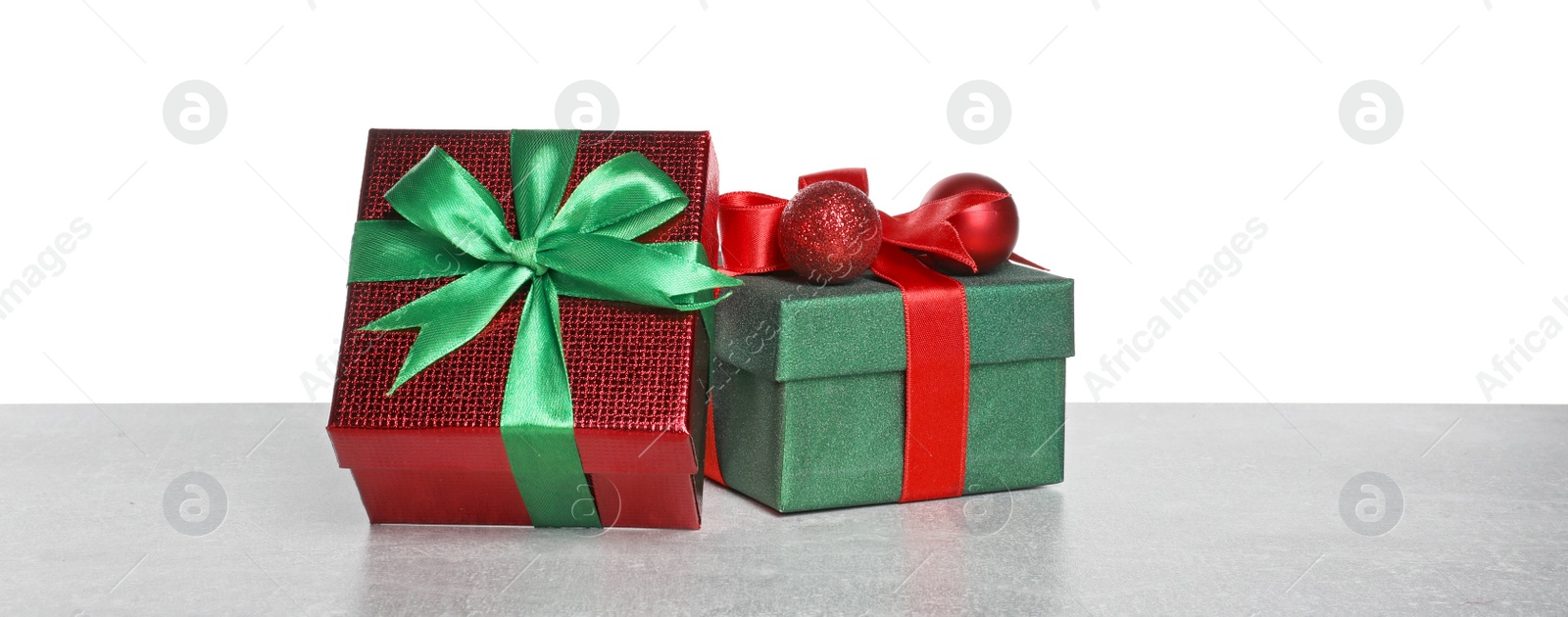 Photo of Christmas gifts in beautiful decorated boxes on grey table against white background